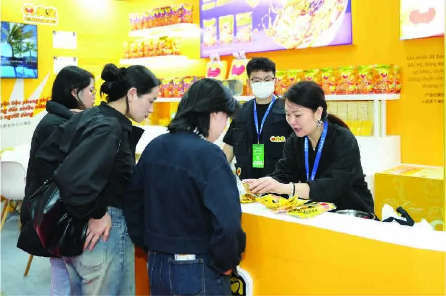 Visitors sampling snacks at an exhibitor booth at Vietfood Hanoi 2025
