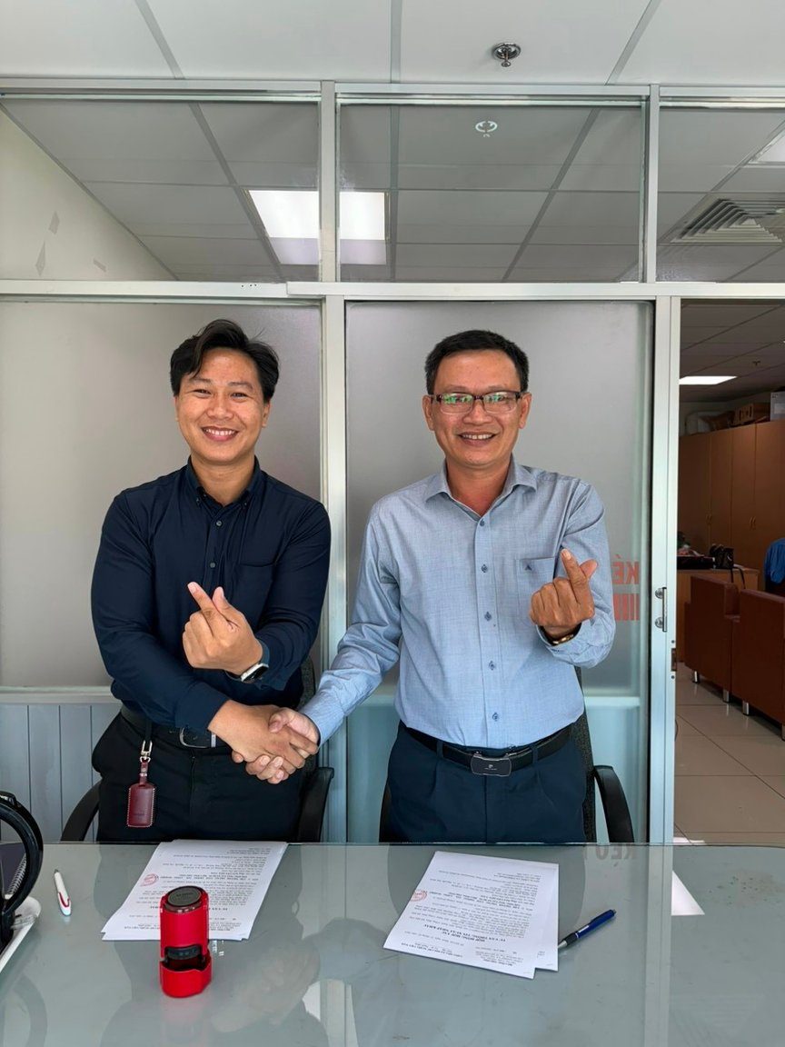Maximillien Quan Pham shaking hands with a partner after signing a cooperation agreement, documents and company seal on the table